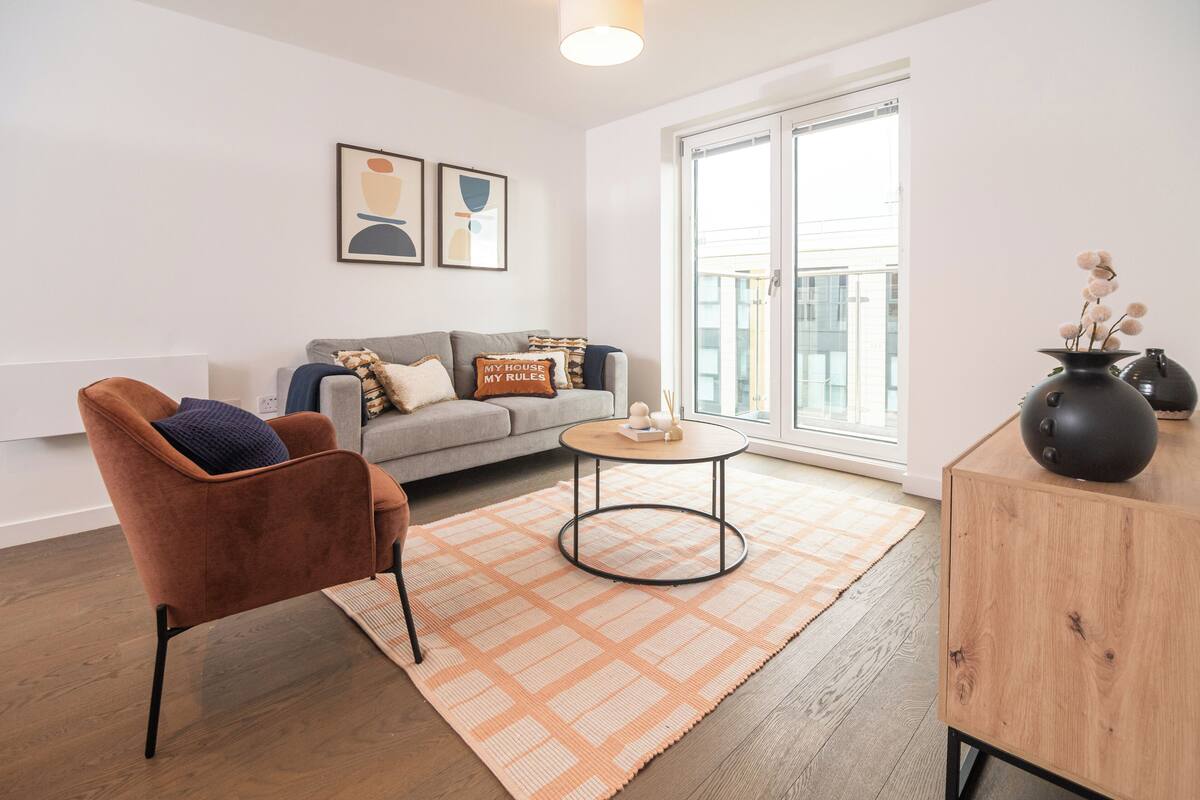 A modern living room with a sofa, armchair, coffee table, and a large window.