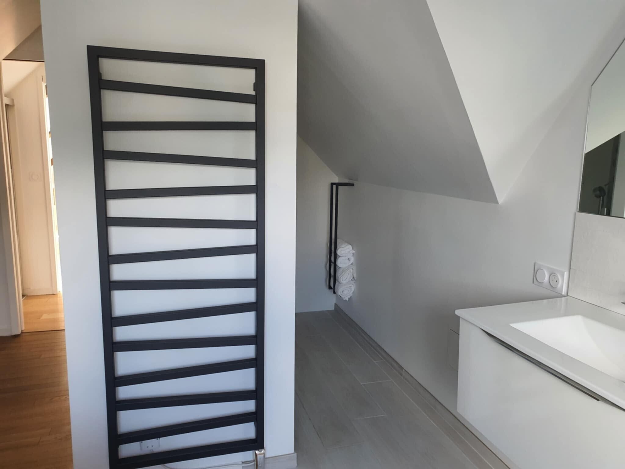 Une salle de bain moderne avec un lavabo blanc, un miroir et un porte-serviettes.