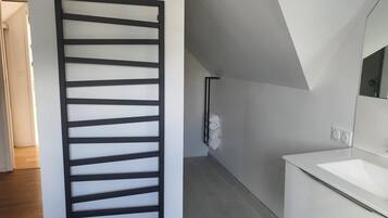 Une salle de bain moderne avec un lavabo blanc, un miroir et un porte-serviettes.