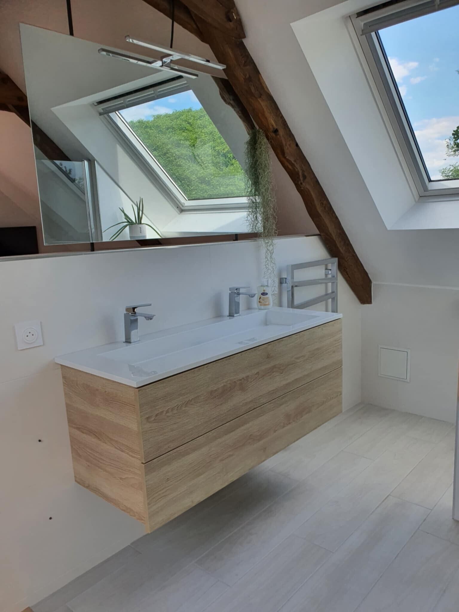 Une salle de bain moderne dotée d’un puits de lumière, d’un meuble-lavabo en bois et d’un grand miroir.