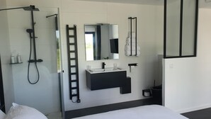 Een moderne badkamer met een douche, een wastafel, een spiegel en een handdoekrek.