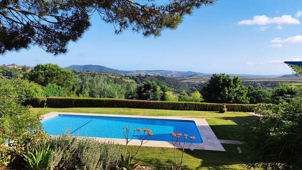 A rectangular swimming pool with a clear blue water surface, surrounded by well-manicured grass and hedges, set against a backdrop of rolling hills and a clear sky. - Quinta El Molino - Refuge with Swimming Pool in Nature  (Avessada)