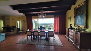 A dining area with a table set for four, a chandelier, and a view of the outdoors. - Quinta El Molino - Refuge with Swimming Pool in Nature  (Avessada)