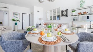 A modern dining area with a round table set for four, surrounded by blue upholstered chairs. - Versilian Tuscan coast escape (Viareggio)