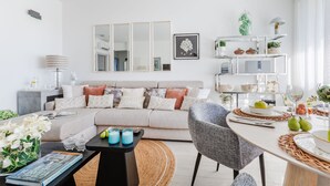 A modern living room with a sofa, a dining table set for two, and a bookshelf. - Versilian Tuscan coast escape (Viareggio)
