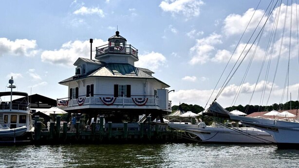 A white building with a balcony and a tower, surrounded by boats and a dock. - The Snuggery Inn & Suites Captain`s Quarters (Saint Michaels)