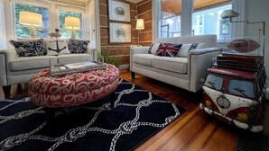 A cozy living room with two sofas, a patterned ottoman, and a vintage suitcase as a coffee table. - The Snuggery Inn & Suites Captain`s Quarters (Saint Michaels)