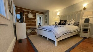 A bedroom with a bed, bedside tables, a mirror, and a wooden wall. - The Snuggery Inn & Suites Captain`s Quarters (Saint Michaels)