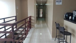 Un pasillo de hotel con una escalera, una máquina de café y dos taburetes de bar.
