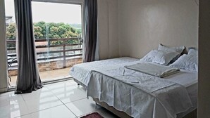 Un dormitorio con cama, ventana con cortinas y aire acondicionado.