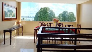 Un comedor con un ventanal grande, un cuadro en la pared y una mesa con sillas.