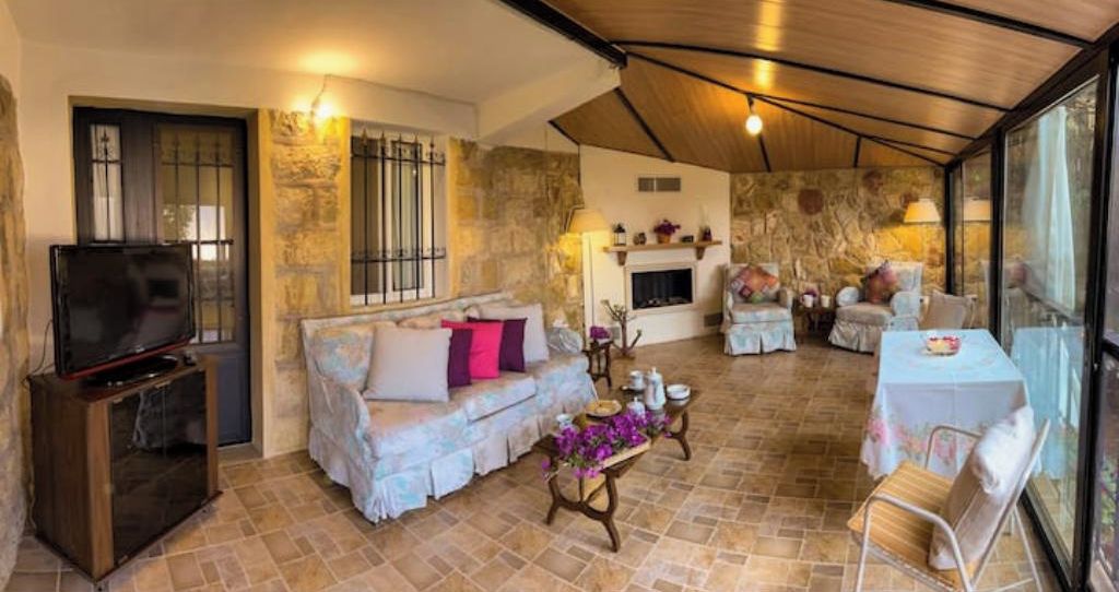 A cozy living room with a sofa, a coffee table, and a TV. There is a fireplace and a dining area with a table and chairs.