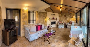 Una sala de estar acogedora con un sofá, una mesa de centro y un televisor. Hay una chimenea y una zona de comedor con una mesa y sillas.