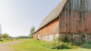 Ein großer, rustikaler Schuppen mit einem steilen Satteldach und einem Steinfundament.