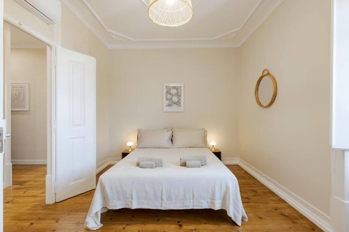 Un dormitorio con una cama grande, dos mesitas de noche con lámparas, una puerta y un adorno circular en la pared.