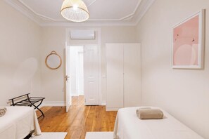 Una habitación con cama, lámpara colgante, puerta y un cuadro en la pared.