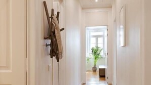 Un pasillo con piso de madera, paredes blancas y una puerta a la izquierda.