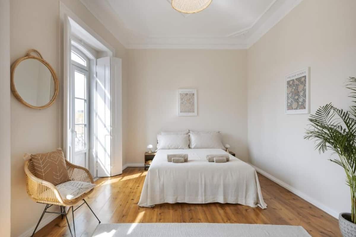 Un dormitorio con una cama grande, una silla, un espejo y una planta.