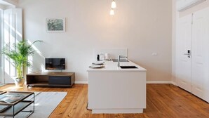 Una cocina moderna con una isla blanca, suelo de madera, un televisor de pantalla plana y una planta en maceta.