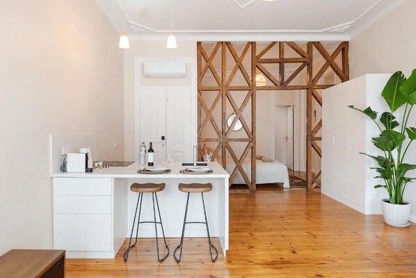 A modern kitchen with a white countertop, two stools, and wooden beams in the background.