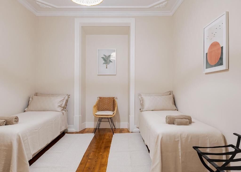Une chambre avec deux lits, une chaise et un tableau encadré au mur.