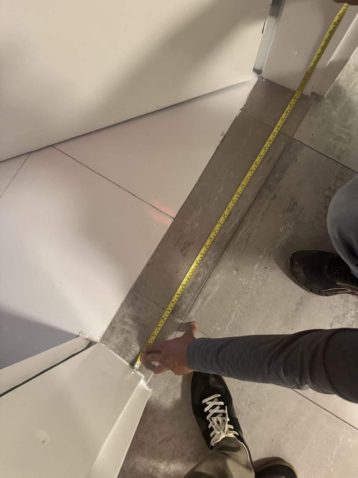 Eine Hand misst eine Ecke mit einem gelben Maßband.