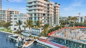 Ein mehrstöckiges Hotel mit Balkonen, eine Marina mit Booten und ein Baugerüst.
