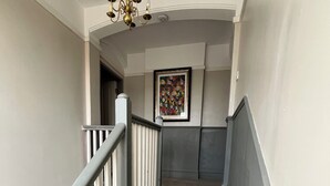 Un escalier recouvert d’une moquette à rayures, un lustre et une œuvre d’art encadrée accrochée au mur.