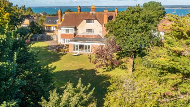 Une grande maison avec une vaste pelouse et une vue sur la mer.