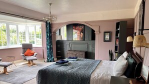Une chambre à coucher avec un grand lit, une chaise, un bureau et une bibliothèque.