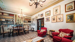 A cozy living room with a patterned floor, a chandelier, red armchairs, and a dining area with wooden furniture. - Casa Eda, in the green hills of Lucca and 5 minutes from the historic center (Lucca)