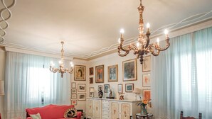 A dining area with a wooden table and chairs, a chandelier, and a red sofa. - Casa Eda, in the green hills of Lucca and 5 minutes from the historic center (Lucca)