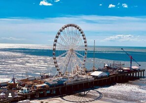 Ein großes Riesenrad mit Blick auf das Meer und einen Pier mit verschiedenen Gebäuden.