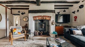 A cozy living room with a fireplace, a sofa, a television, and a bookshelf.
