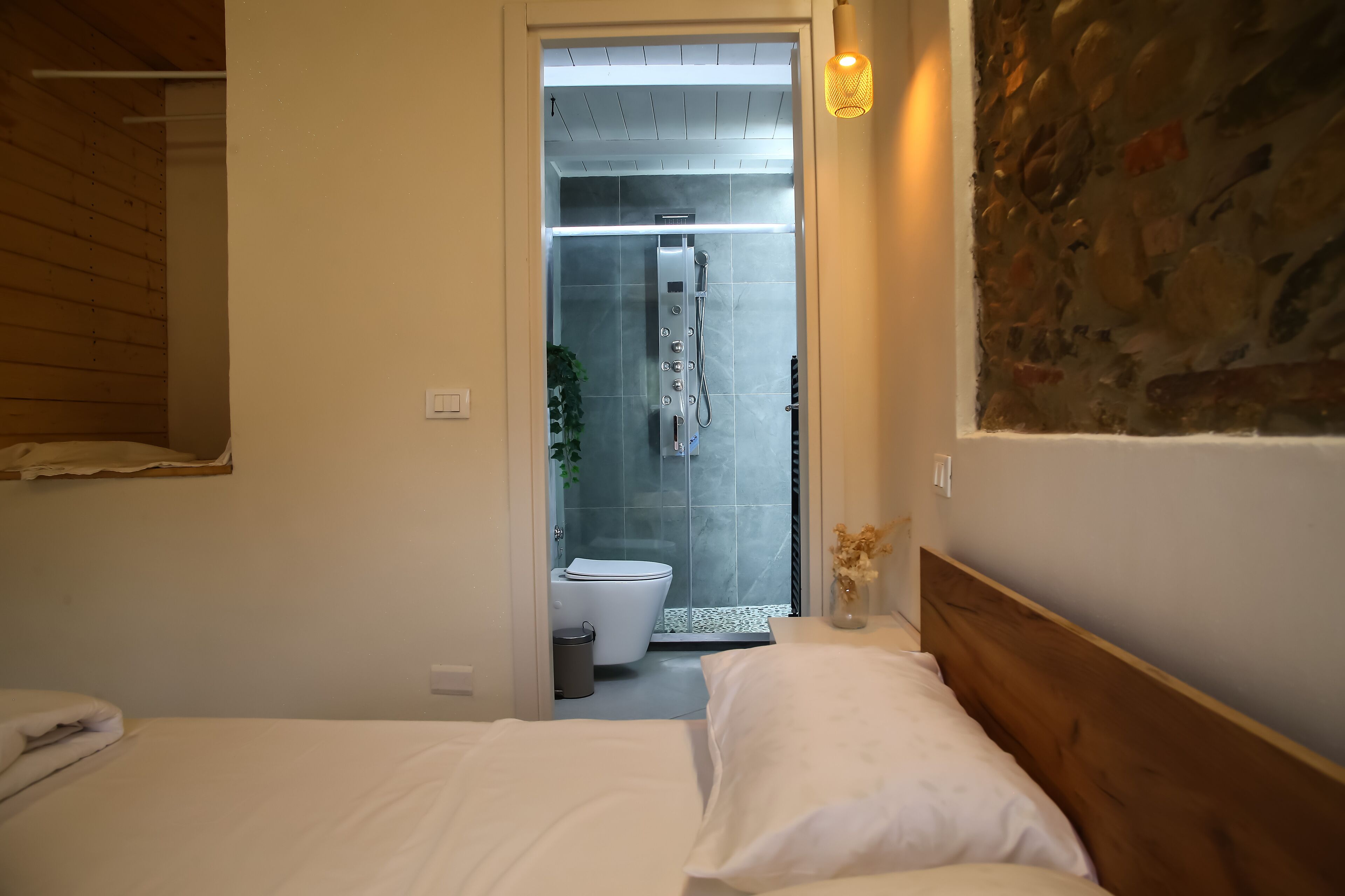 A bedroom with a wooden headboard, a bed with white linens, and a bathroom visible through an open door.