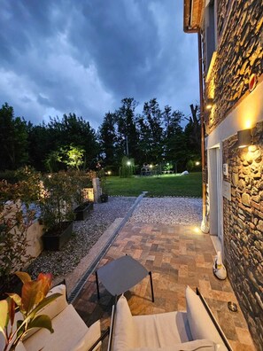Un patio con posti a sedere all'aperto, un muro in pietra e vista su una zona verde.