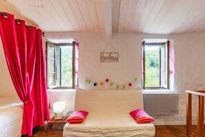 Un dormitorio con una cama, dos ventanas, un letrero en la pared y una guirnalda de luces de colores.