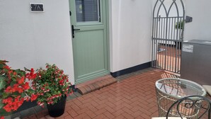 A green door with a window, a metal gate, and a potted plant with red flowers. - The Nook is a cosy holiday let in Rostrevor at the foot of the Mourne mountains. (Rostrevor)