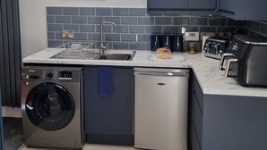 A compact kitchen with a washing machine, dishwasher, and a toaster. - The Nook is a cosy holiday let in Rostrevor at the foot of the Mourne mountains. (Rostrevor)
