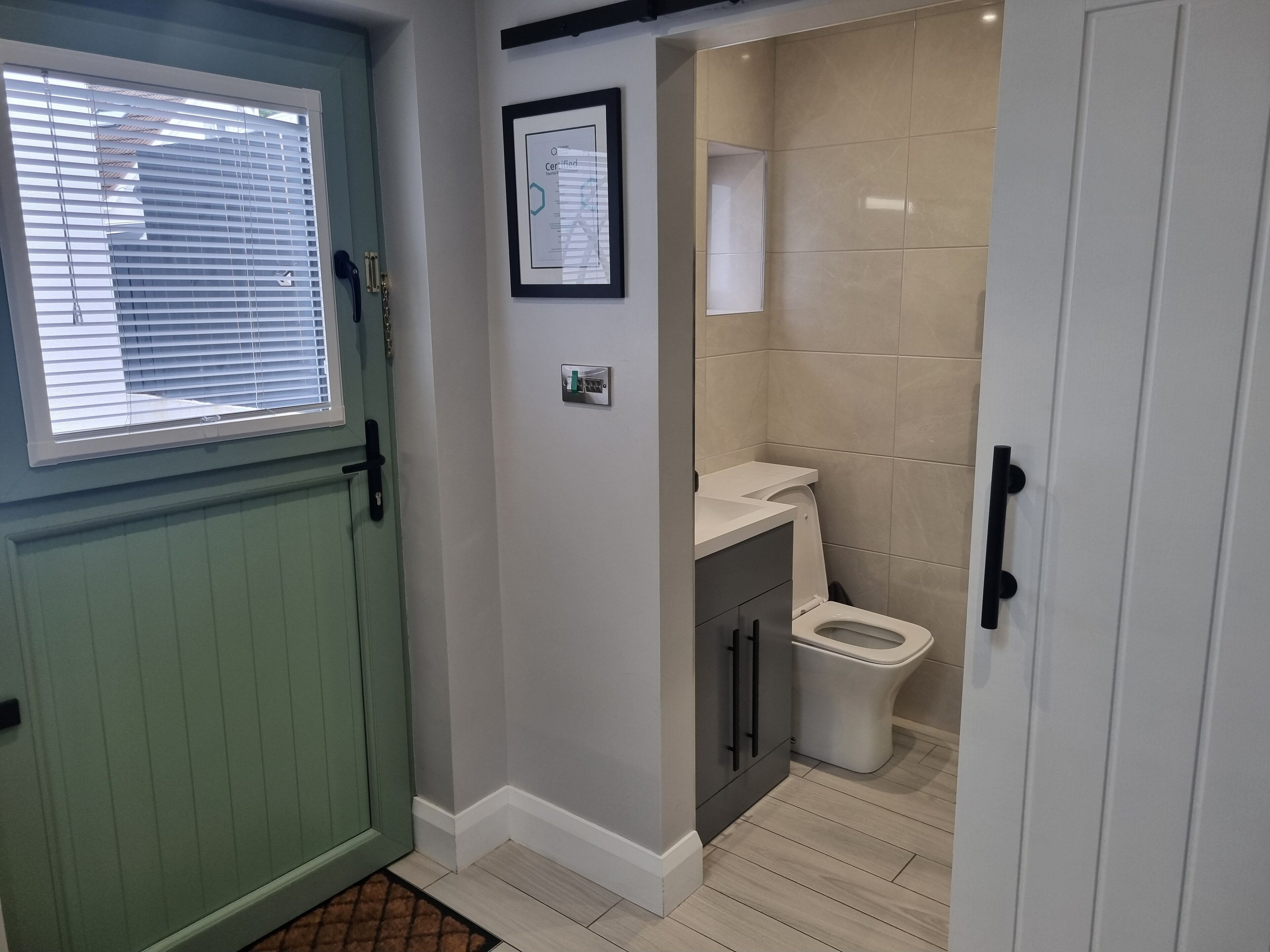 A bathroom with a toilet, a sink, and a framed certificate on the wall.