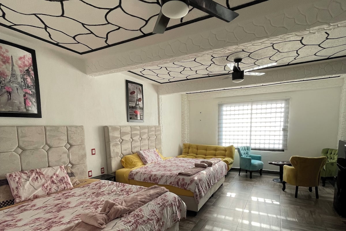 Un dormitorio con dos camas, un ventilador de techo y una ventana con persianas.
