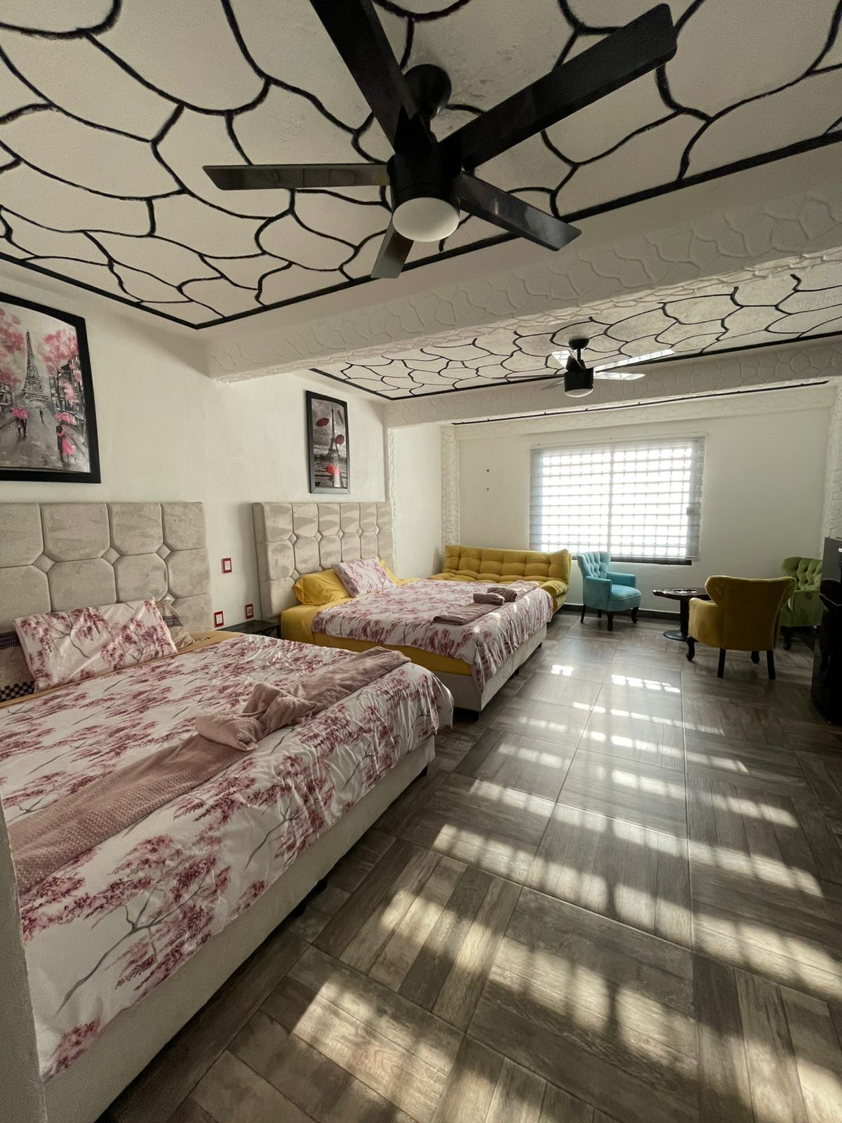 A bedroom with two beds, a sofa, and a ceiling fan.