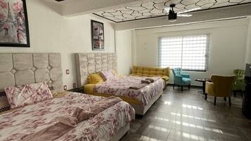 A bedroom with two beds, a sofa, and a ceiling fan.