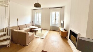 A living room with a sofa, a coffee table, a TV, and a fireplace. - Large duplex with garden in Auray town center (Auray)