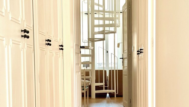 A hallway with white doors, a wooden floor, and a staircase leading to a balcony. - Large duplex with garden in Auray town center (Auray)