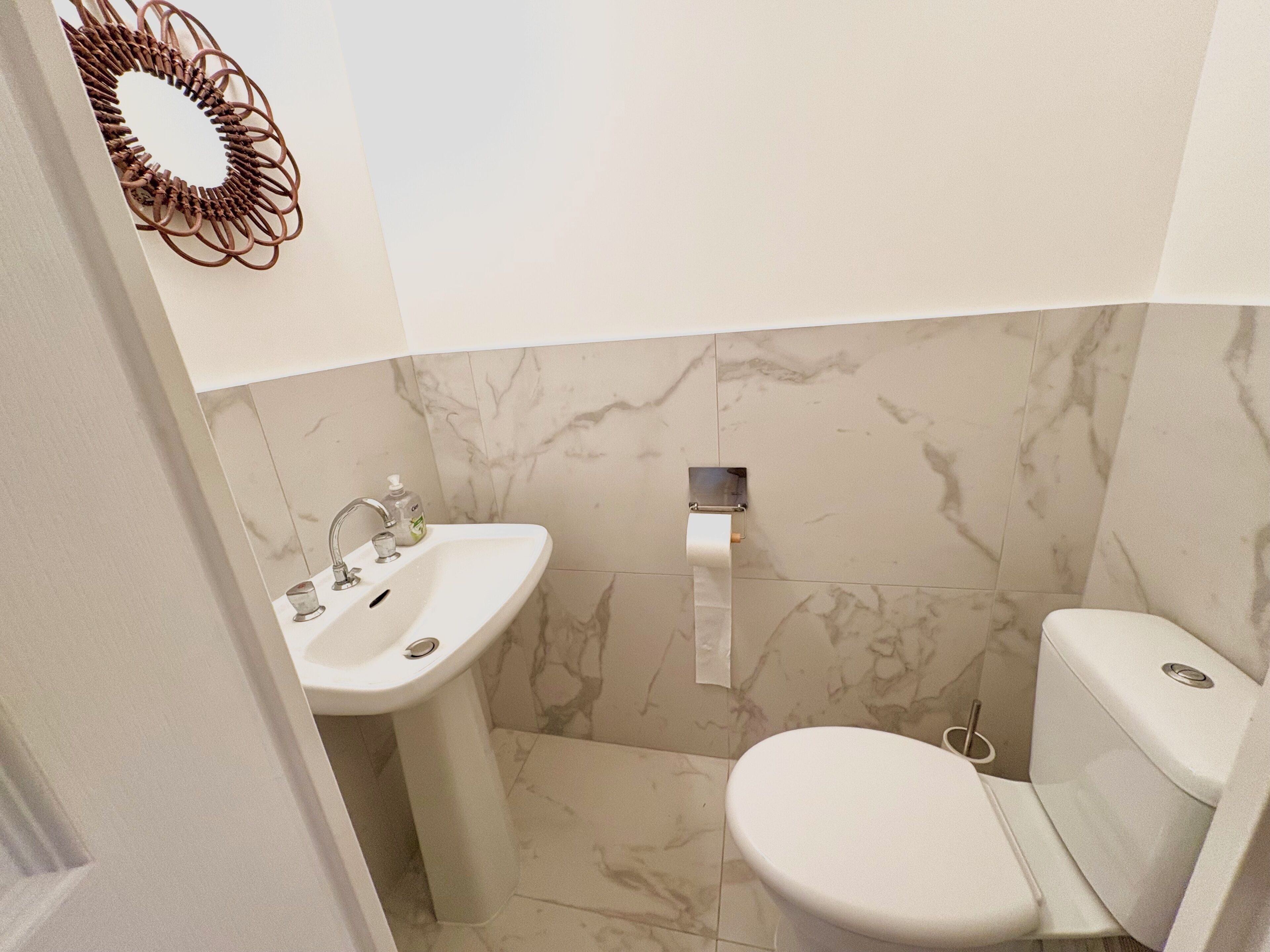 A bathroom with a sink, toilet, and marble-tiled walls.