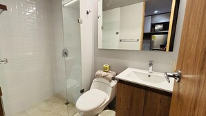 Een moderne badkamer met een douchecabine van glas, een toilet en een wastafel met spiegel erboven.