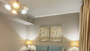 A bedroom with a bed, two bedside tables, a chandelier, and two wall-mounted paintings. - Stately State Street Abode 2 (Bowling Green)