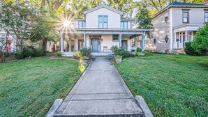 A two-story house with a front porch, a driveway, and a well-maintained lawn. - Stately State Street Abode 2 (Bowling Green)