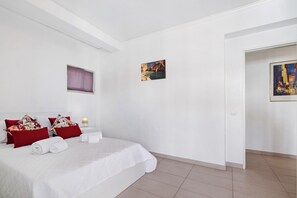 A hotel room with a bed, pillows, a painting, and a window.